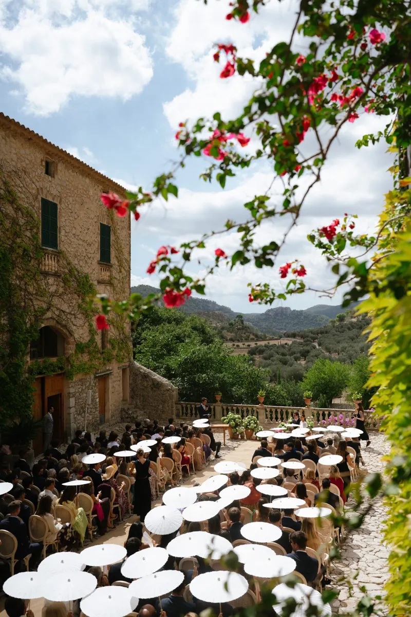 Wedding cocktail hour under white paper parasols at Comassema, Mallorca