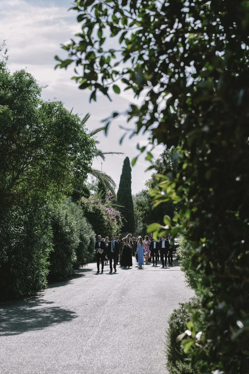Guests gathered at the end of a gravel avenue between hedges and cypresses, Biniagual, Mallorca