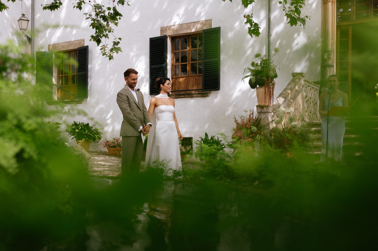 Charlotte and Rhodri hand in hand, seen through the foliage at Jardines de Alfabia, Mallorca