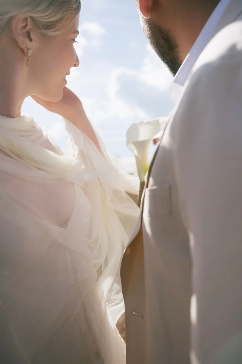 The bride holding a calla lily as they face each other against the sky, Finca Binissatí, Mallorca