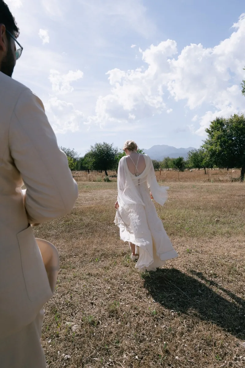 The bride walking out across the dry field under a wide sky, Finca Binissatí, Mallorca