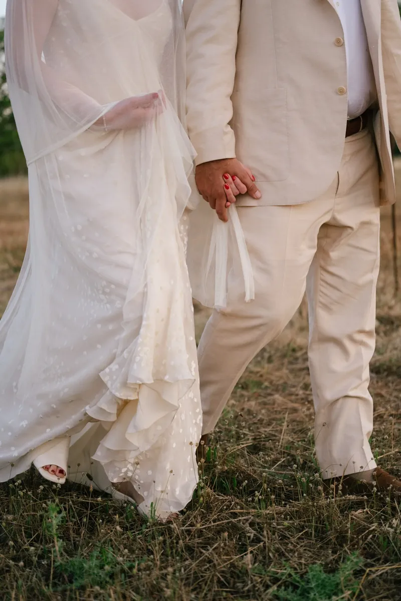 The couple’s joined hands between her lace dress and his cream suit, Finca Binissatí, Mallorca