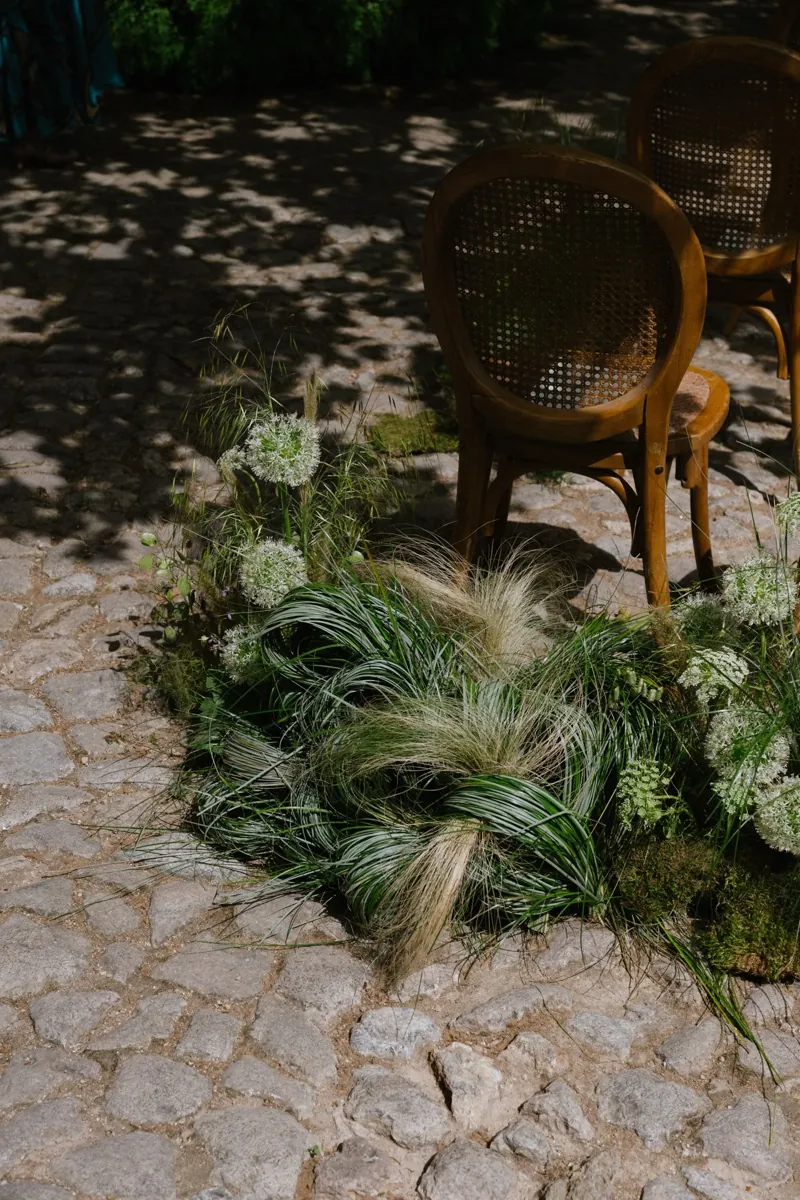 Cane chairs and planted grasses on the stone terrace in dappled shade, Jardines de Alfabia, Mallorca