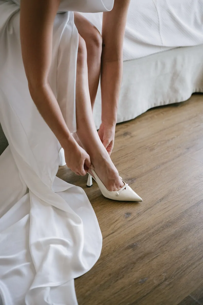 The bride fastening her shoe at the end of the bed, Lume & Co, Génova, Mallorca