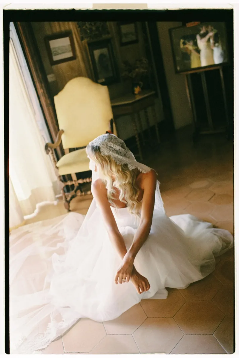 The bride seated on the tiled floor of the drawing room, shot on 35mm film, Son Marroig, Deià, Mallorca